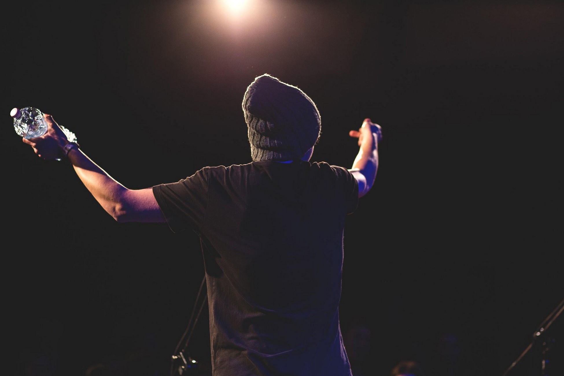 A person on stage with arms raised, holding a water bottle